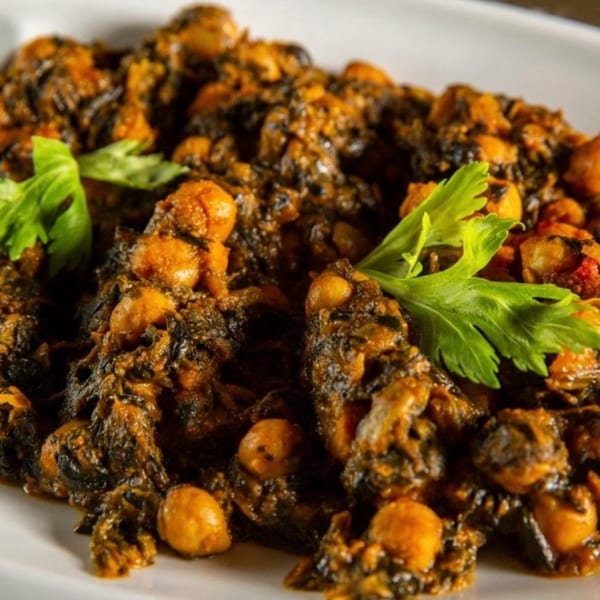 Close-up of a rich, dark Indian chickpea and spinach dish, garnished with fresh parsley.